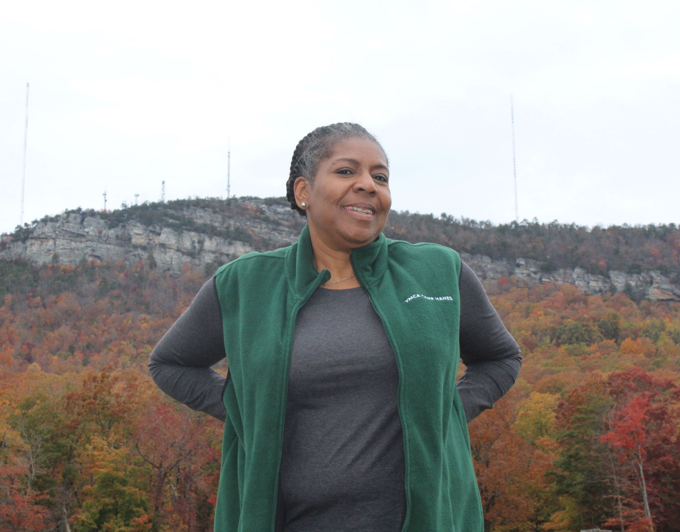 Woman in front of mountain with green vest