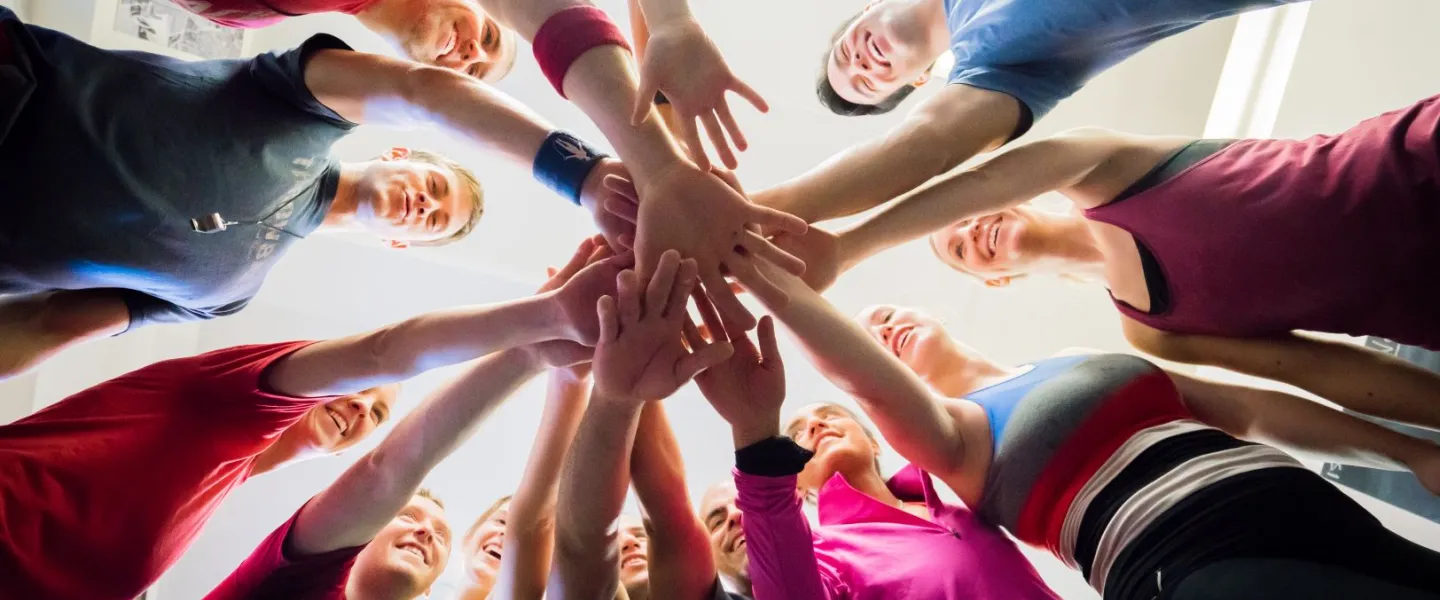 Group of people standing in a circle with their hands in