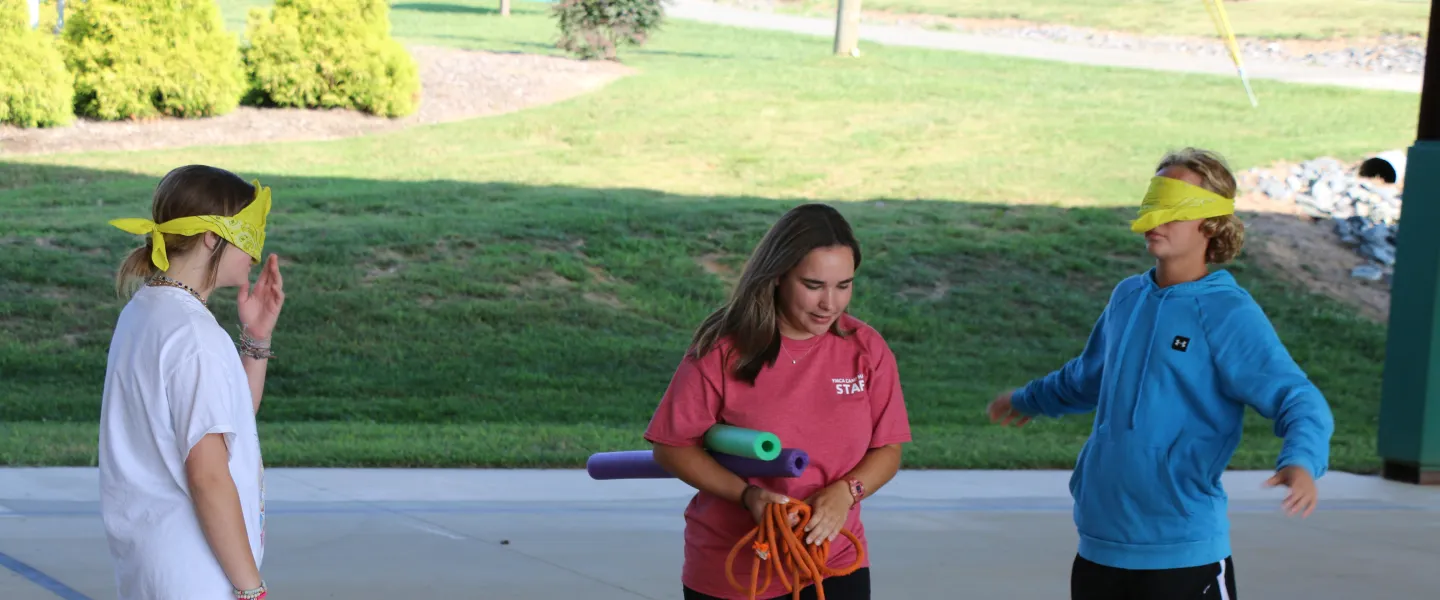 Two students facing each other with Camp Hanes staff in the middle.
