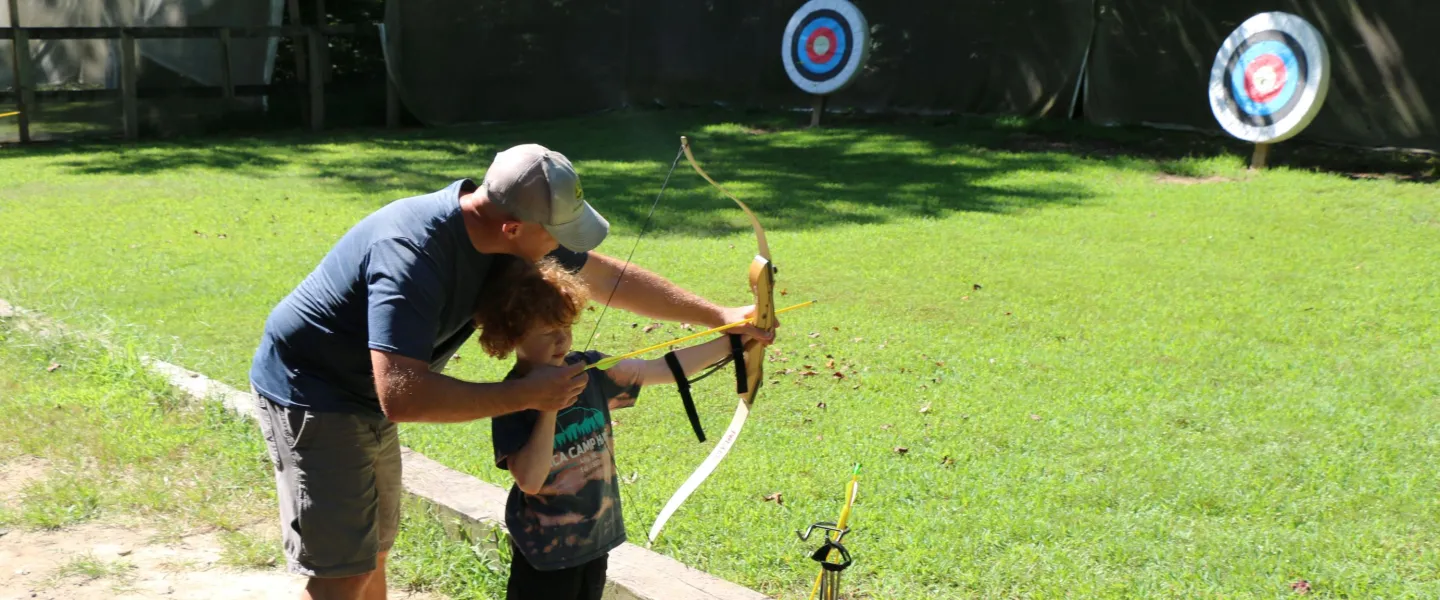 father and son shooting a bow and arrow