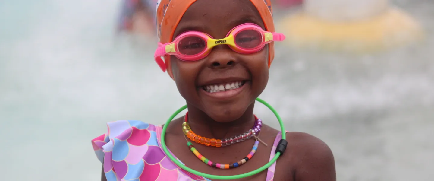 Cute girl black girl in pink goggles and orange swim cap