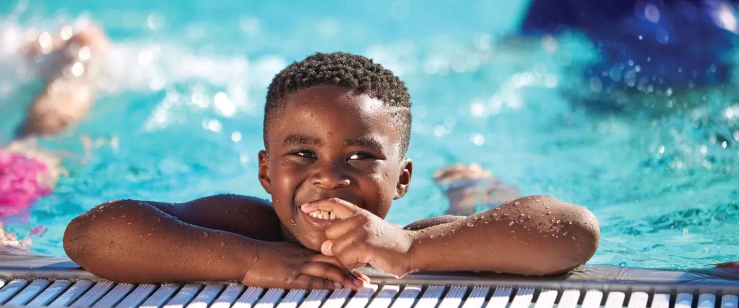 Boy smiling on the side of the pool