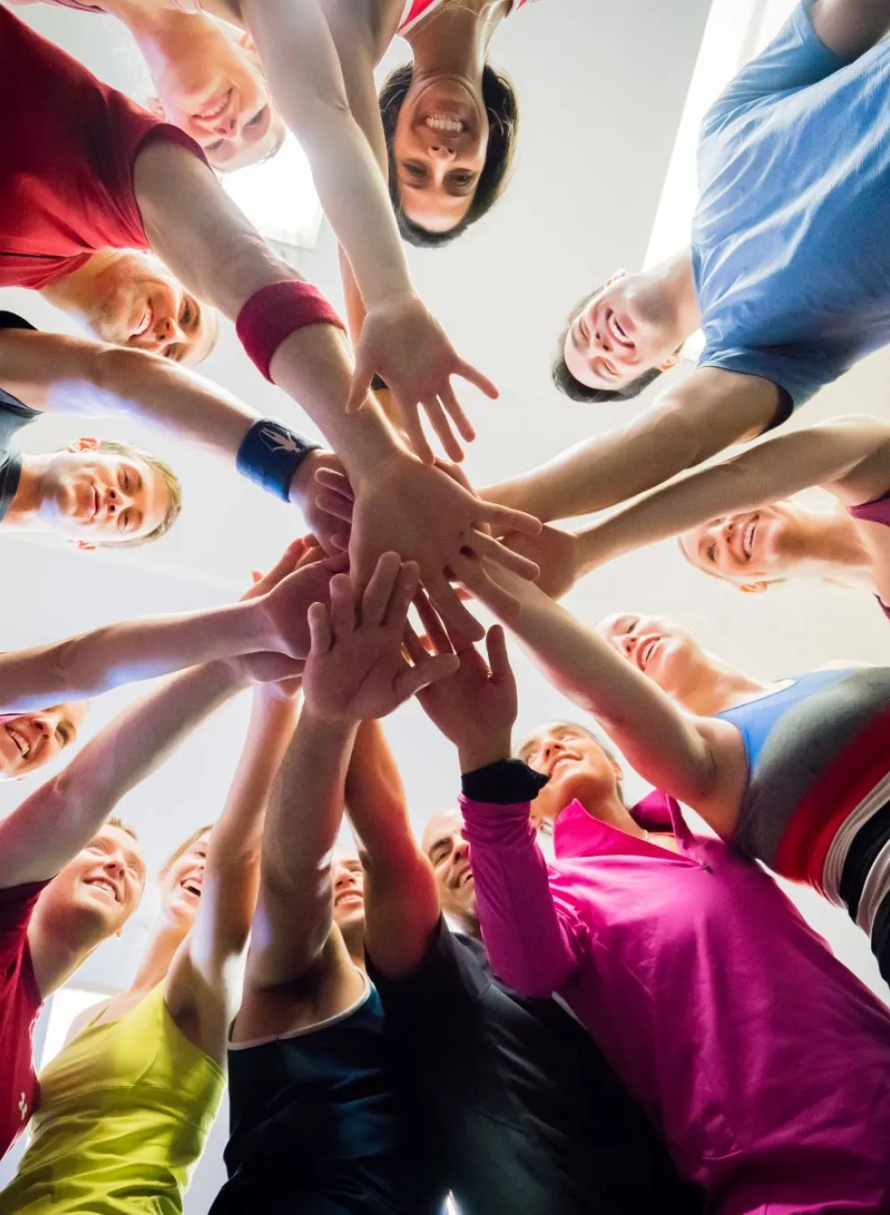 Group of people standing in a circle with their hands in