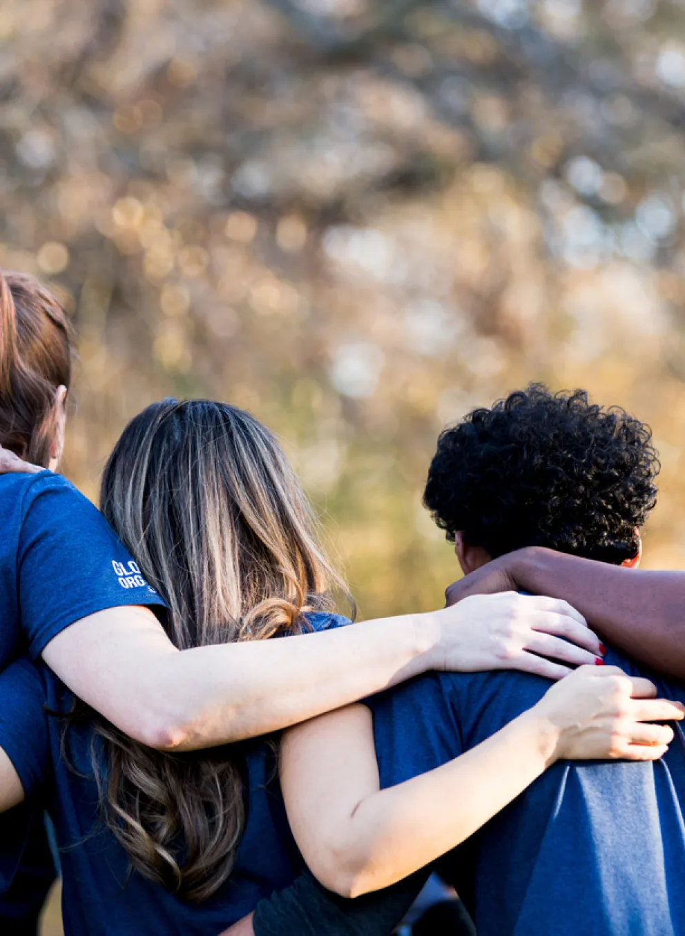 group of young adults diverse interlocking arms from back