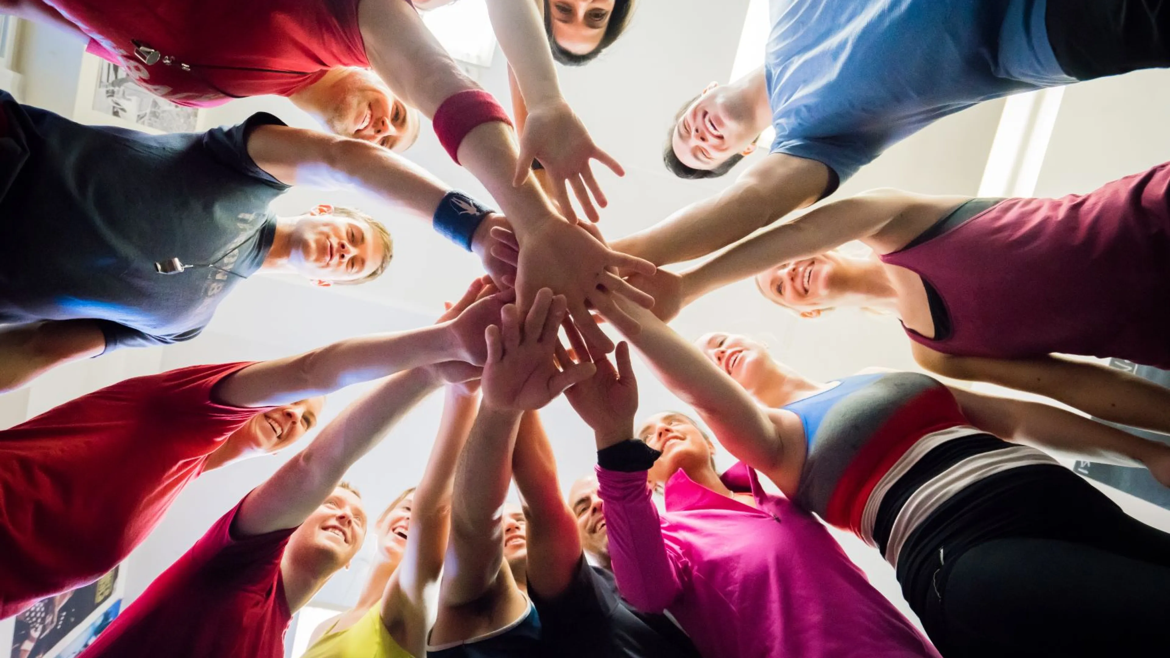 Group of people standing in a circle with their hands in