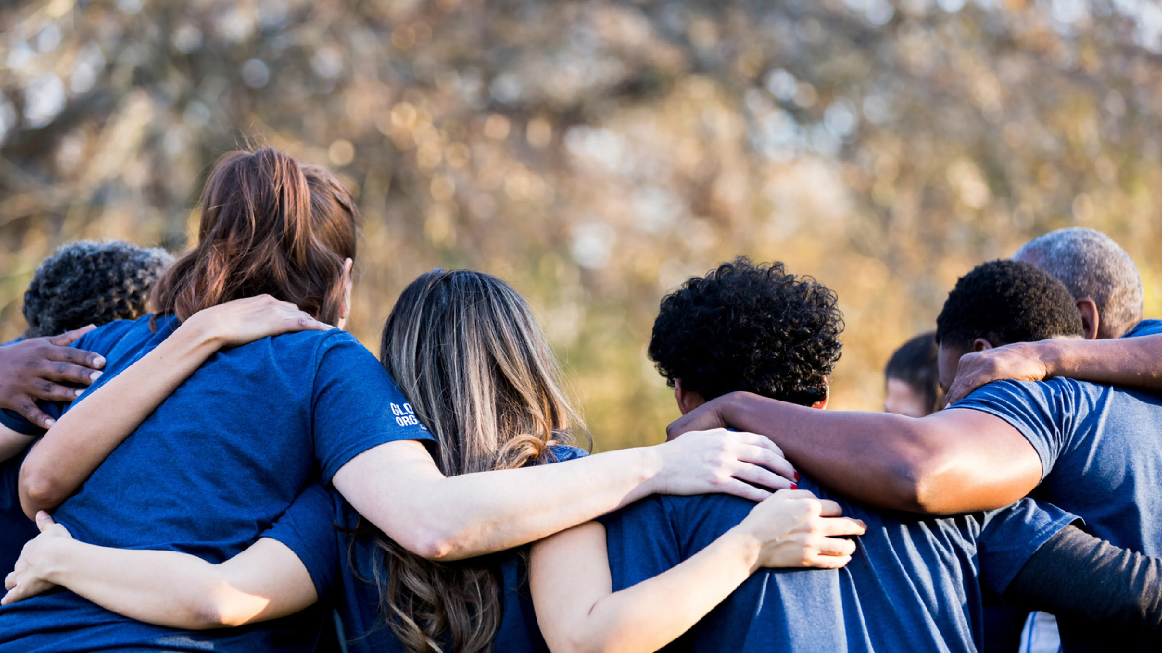 group of young adults diverse interlocking arms from back