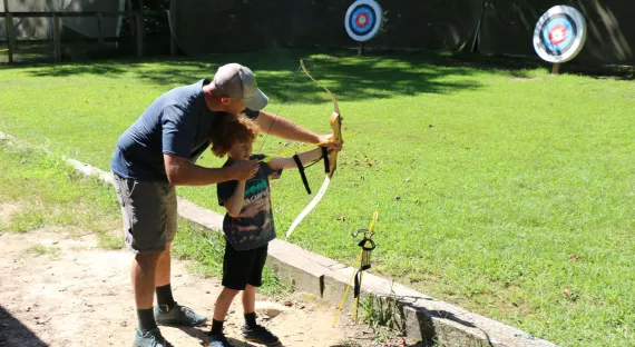 father and son shooting a bow and arrow
