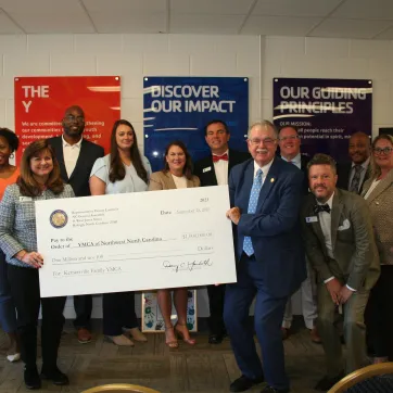 Group of people holding up large check