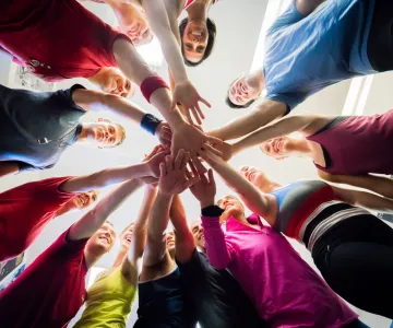 Group of people standing in a circle with their hands in