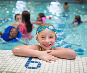 Girl with goggles on her head on the side of the pool