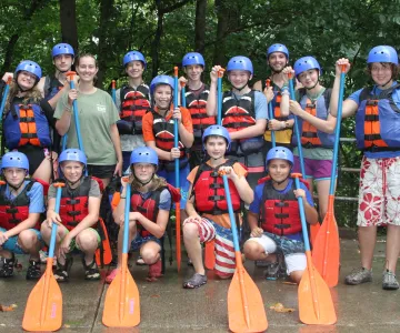 Campers and staff holding paddles before going on a rafting trip.