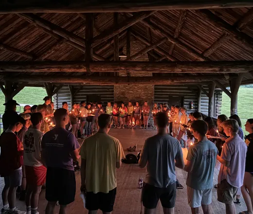Staff in a circle in the Rec Hall holding candles for the end of campfire ceremony and "it only takes a spark" song.