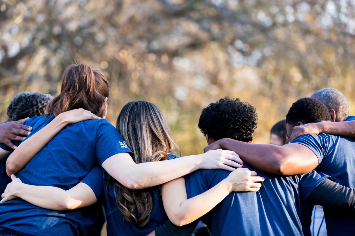 group of young adults diverse interlocking arms from back