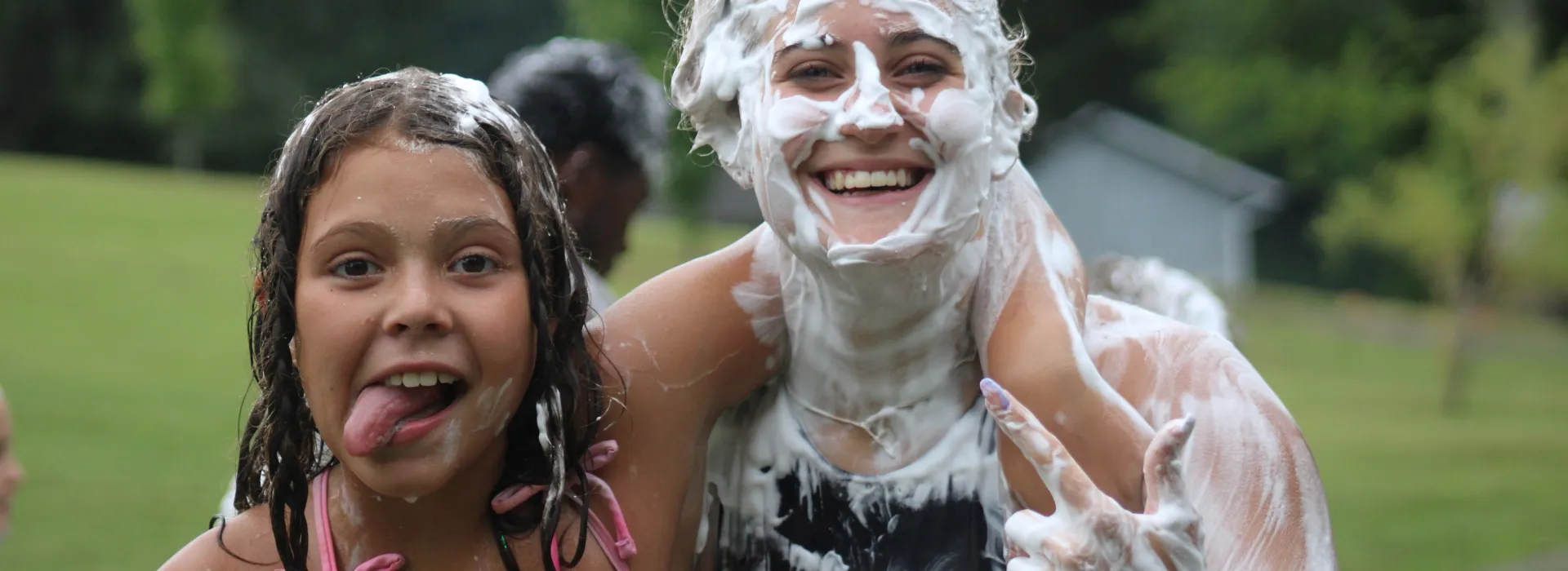 Girl with tong out and another older girl with shaving cream covering her